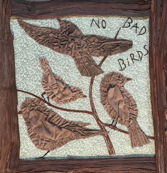 Artwork by Nicandra Galper. Image shows four brown fabric birds appliqued on a blue calico background. The embroidered words 'no bad birds' appear in the upper right.