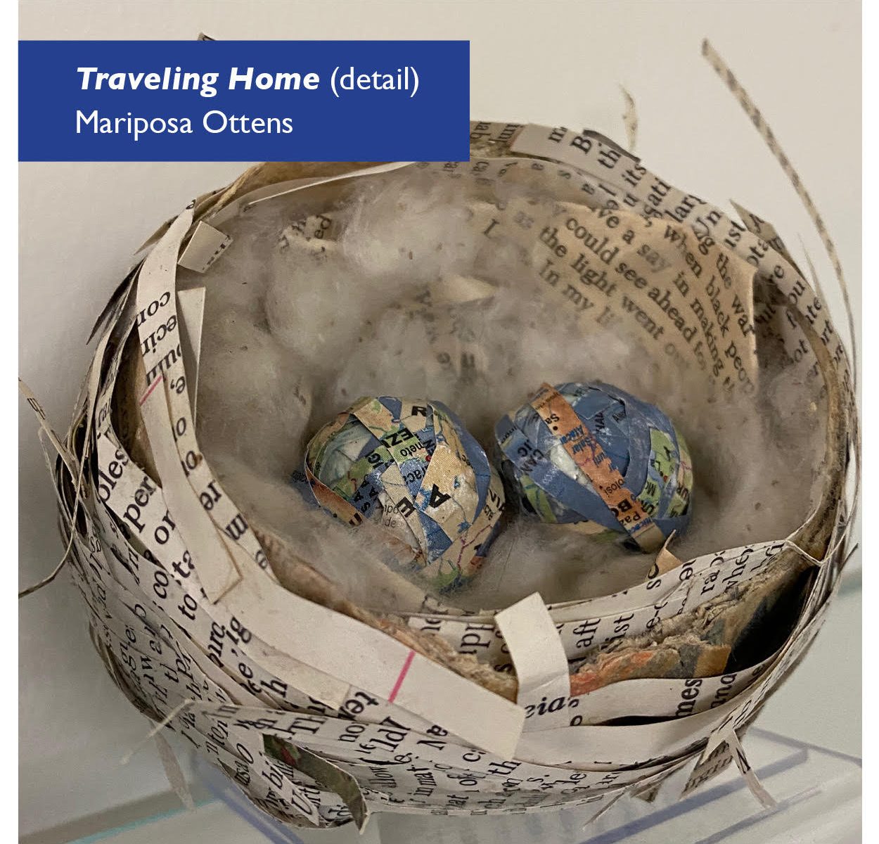 A artist's rendition of a birds nest using strips of paper repurposed from a book. The nest is lined with soft fibers and two "eggs" made of strips of maps rest within. Artist: Mariposa Ottens. Image © and used by permission.