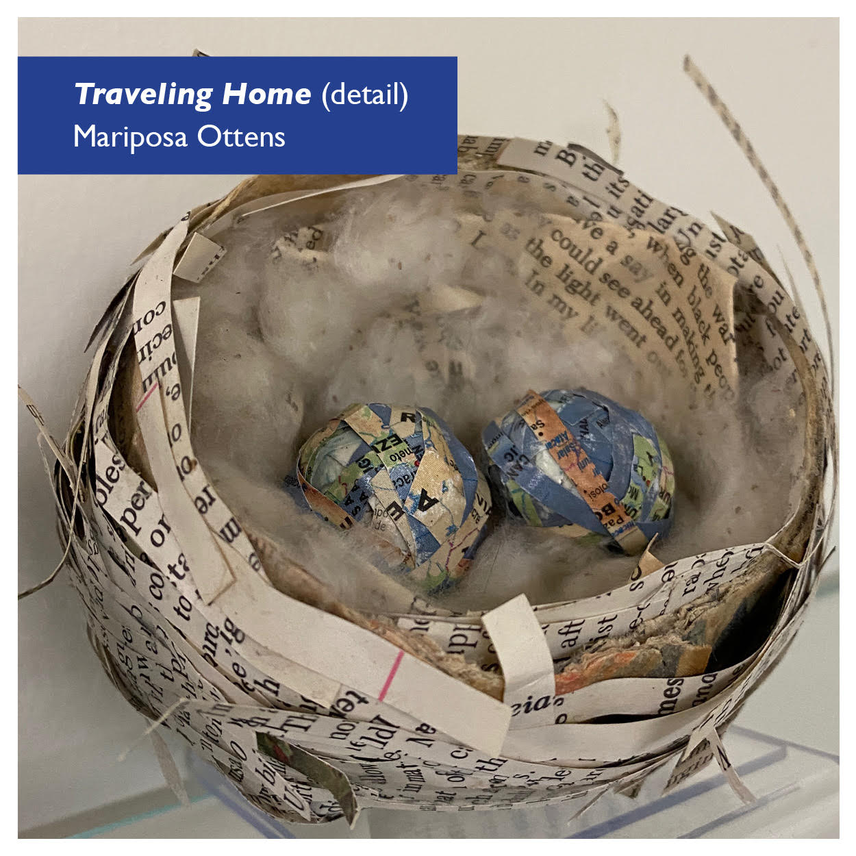 A artist's rendition of a birds nest using strips of paper repurposed from a book. The nest is lined with soft fibers and two "eggs" made of strips of maps rest within. Artist: Mariposa Ottens. Image © and used by permission.