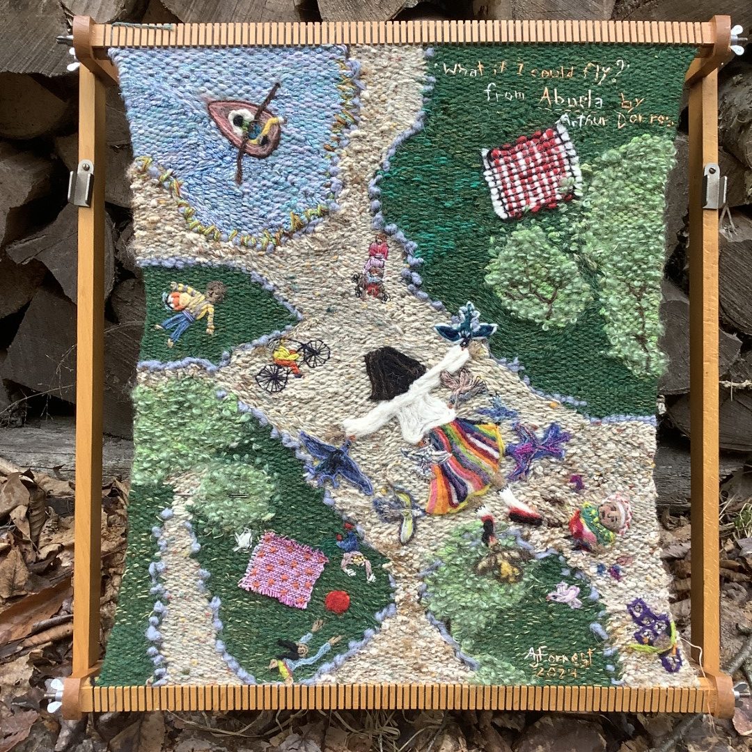 A hand-woven tapestry showing a dark-haired girl in a rainbow skirt flying over a park with birds, bicyclists, pod, paths, trees. She flies without wings or devices. The view is from above the girl, who is facing the park below her. The weaving is still on the loom. Work copyright © 2024 by Alison Forrest and shown here with permission.
