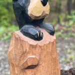 Whittled and painted black bear cub peeking over a stump. Carved by Bob Lindemann.