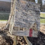 Baba Yaga's Hut in the Green Mountains: white earthenware clay sculpture of ramshackle cabin standing on two chicken legs. Created by Nancy Leeman, 2025, and shown with permission.
