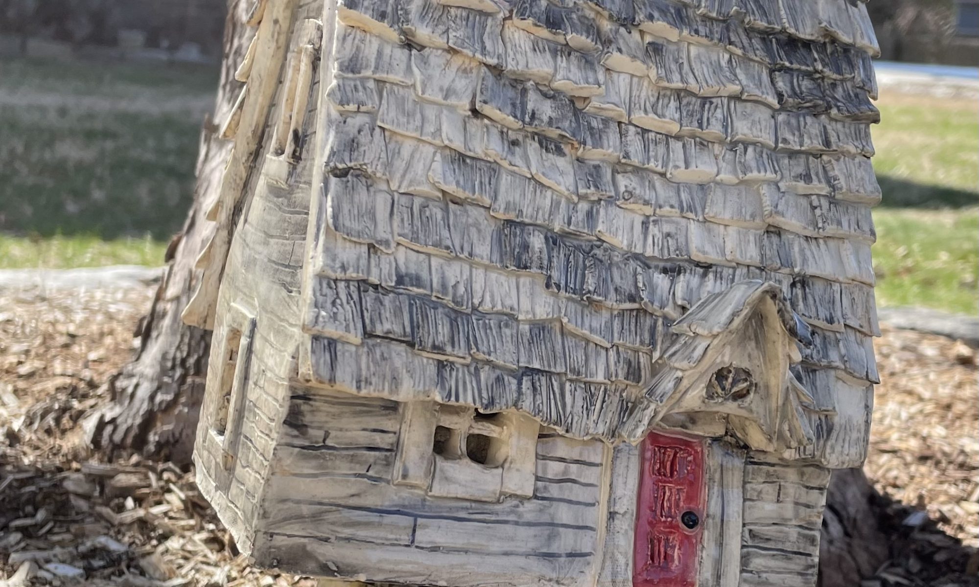 Baba Yaga's Hut in the Green Mountains: white earthenware clay sculpture of ramshackle cabin standing on two chicken legs. Created by Nancy Leeman, 2025, and shown with permission.
